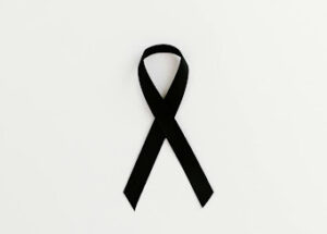 Black ribbon laying flat on an off-white background for skin cancer awareness