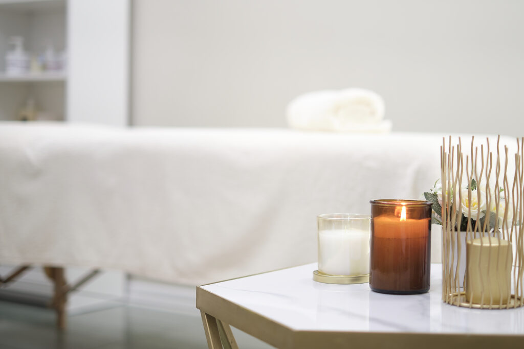 Candles on a table beside a massage table at Bespoke Wellness in Alameda, where clients experience massage benefits like relaxation and better sleep.