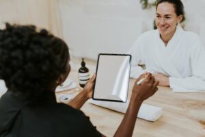 Spa employee discussing massage frequency and facial scheduling with a client at a wellness studio.
